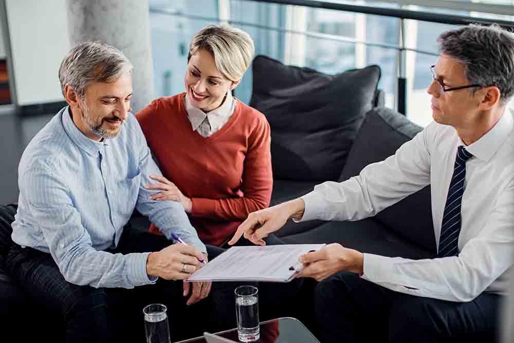 A man asking a couple to sign a contract 