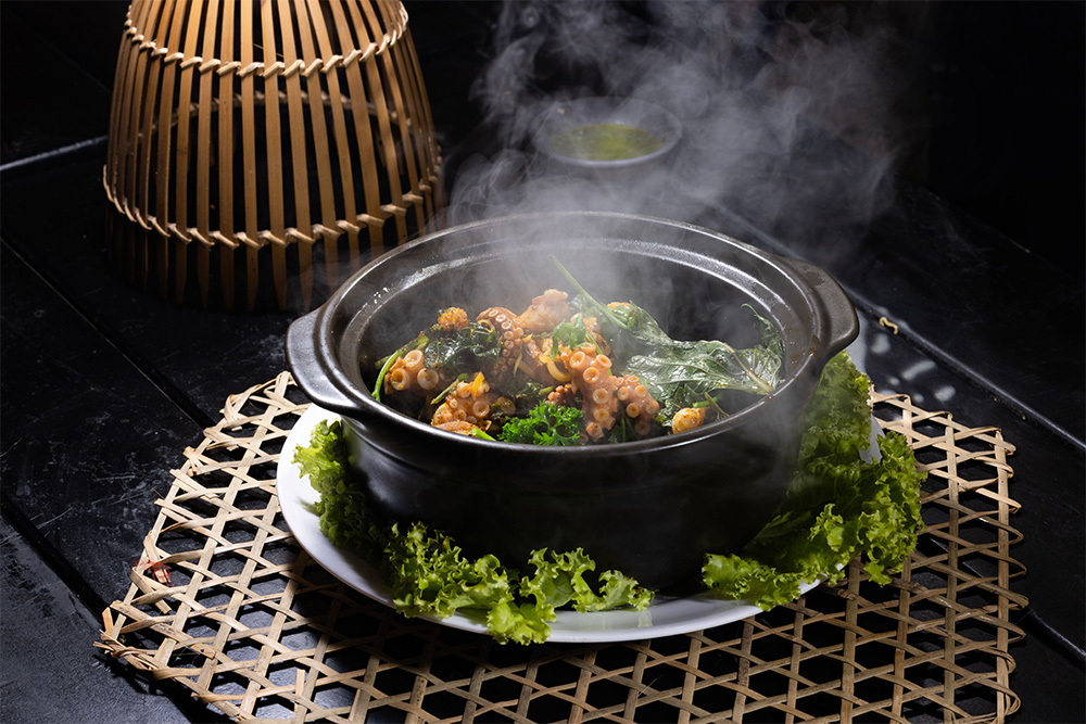  A closeup of a soup with Octopus in a pot on a table 