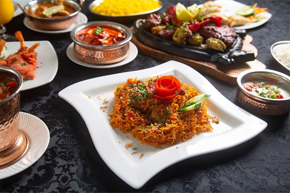 Table with typical Indian dishes, Biryani, chicken curry, tandoori and tikka masala