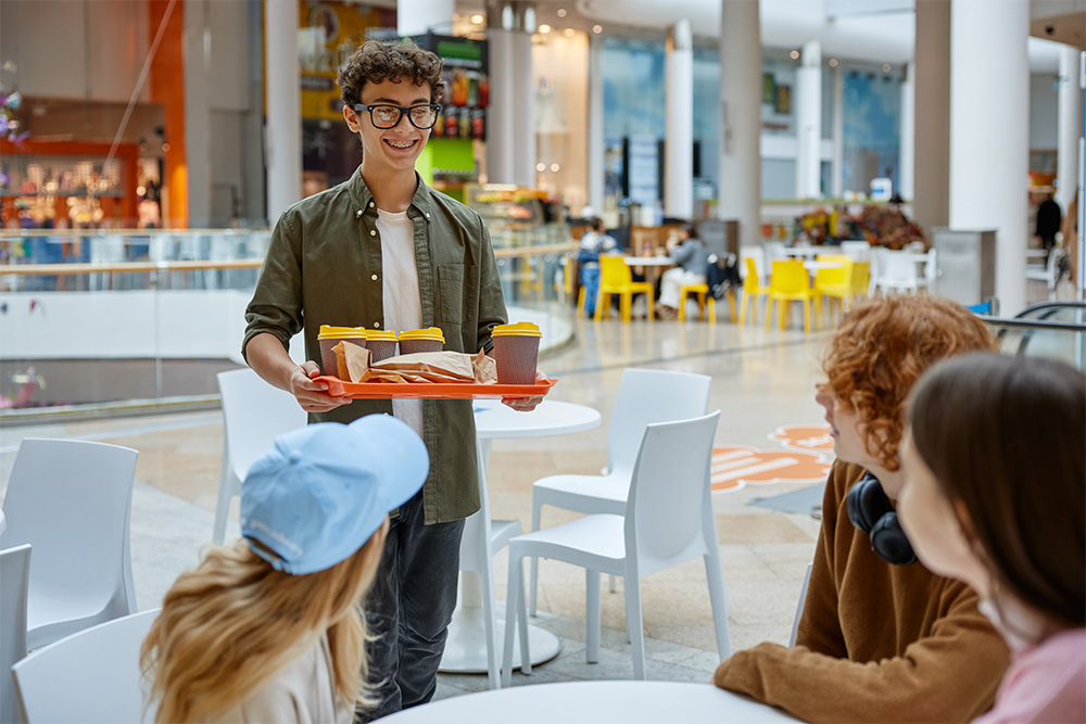 Smiling waitress serving a meal to a businesswoman in the restaurant.