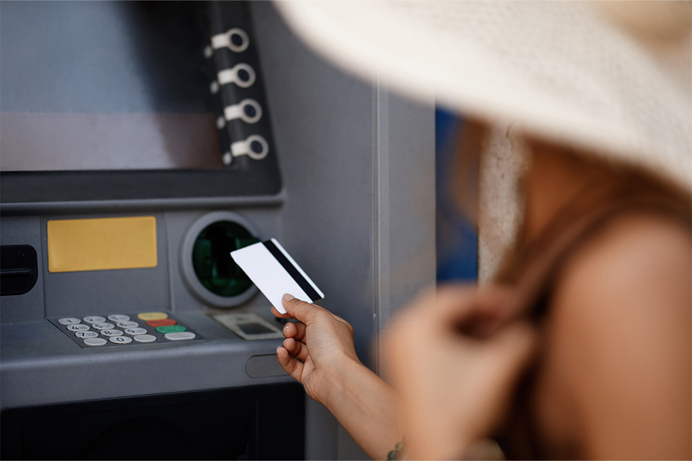 The cropped image of a woman inserting a credit card in an ATM in a mall lobby. Concept of rest, vacation and travelling