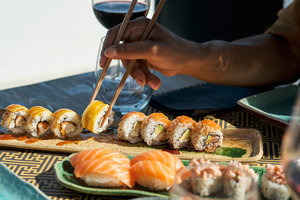 unrecognisable female taking an appetising sushi roll with salmon