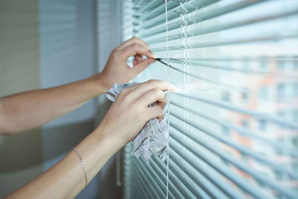 A maid hired through tadbeer services is cleaning blinds