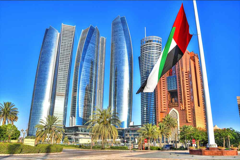 Abu Dhabi buildings and towers with uae flagpost in fron