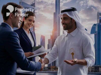 An Arabic man shaking hands with a man in a suit standing next to a woman with files and documents