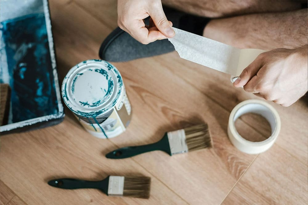 Faceless man unwrapping scotch tape during renovation process at home