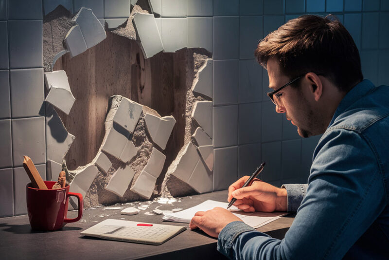 man sitting in front of broken wall 