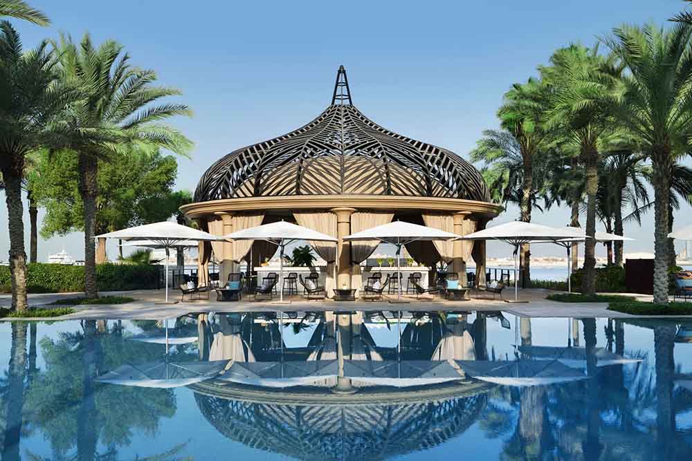 Image of a swimming pool with beach chairs and umbrellas 