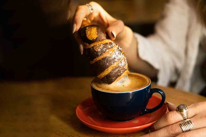 Delicious croissant dipped in hot coffee at a coffee shop in Abu Dhabi 