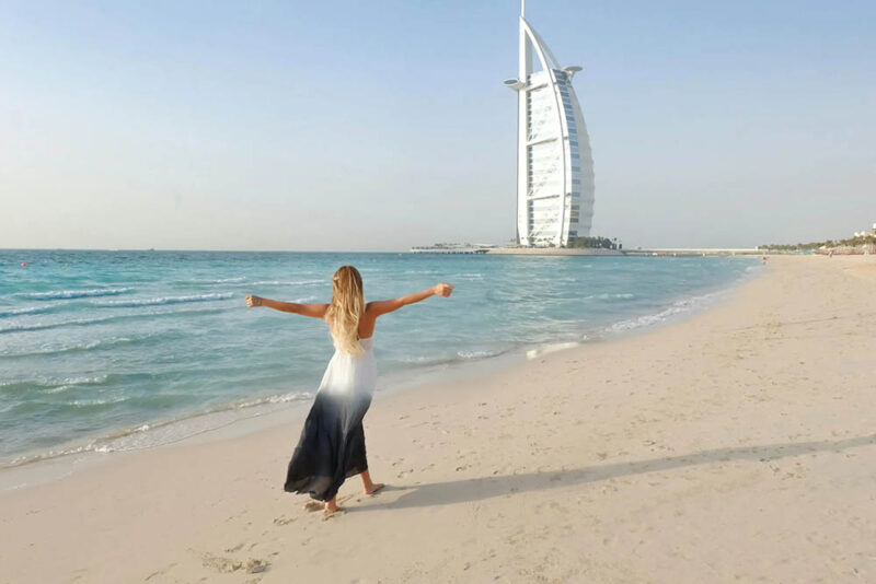 A woman on the beach with a burj al arab in the background 