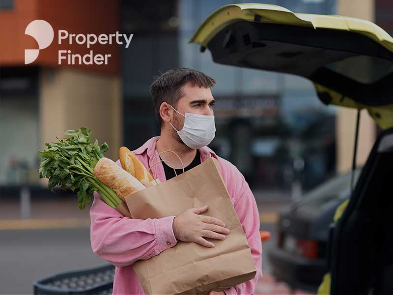 A man holding abag of carrots near a car