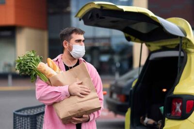 A man holding abag of carrots near a car