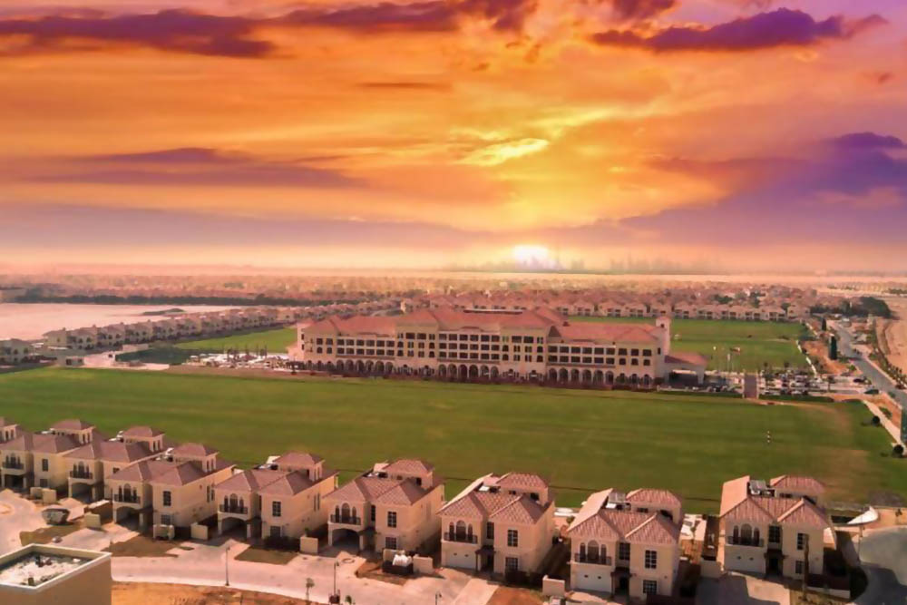 A sunset view of a resort with a garden 