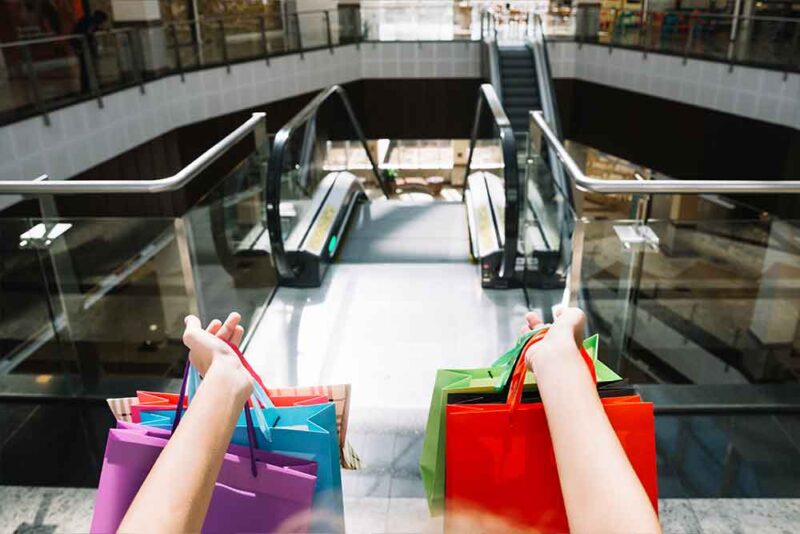 A person on the escalators with shopping bags