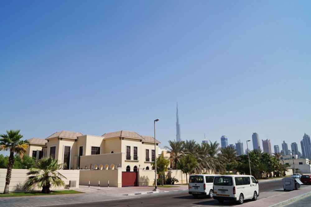 Two cars passing on the road with Dubai’s skyline in the background