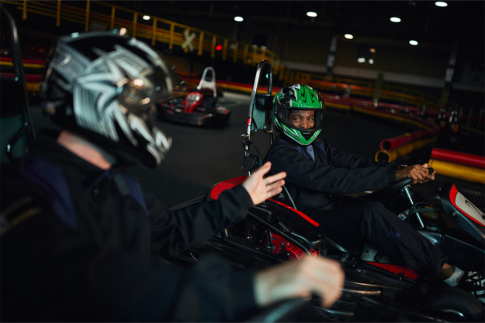 People karting with helmets on a go kart track 