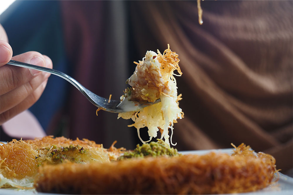 A spoon full of Kunafa with a wipe cream