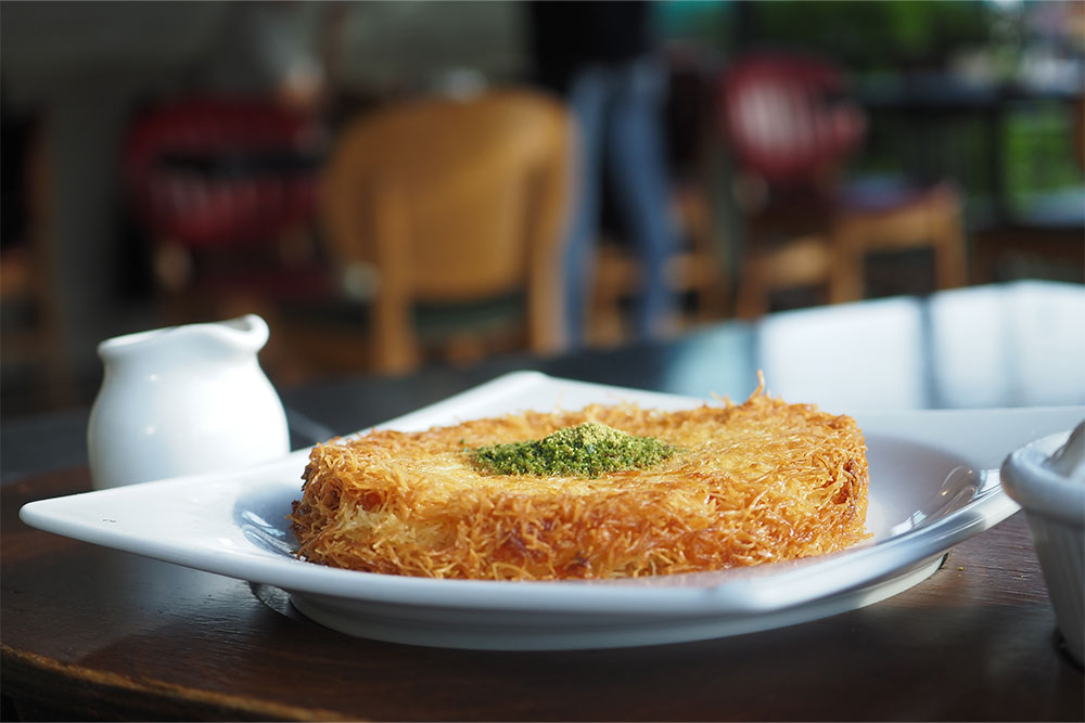  Kunafa served in a white plate with pistachios 