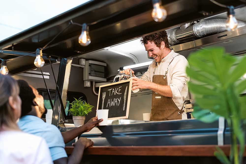 people buying meals from street food truck market 