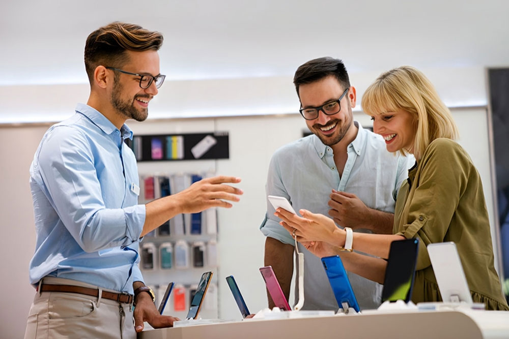 Salesman showing mobile phone to a couple 