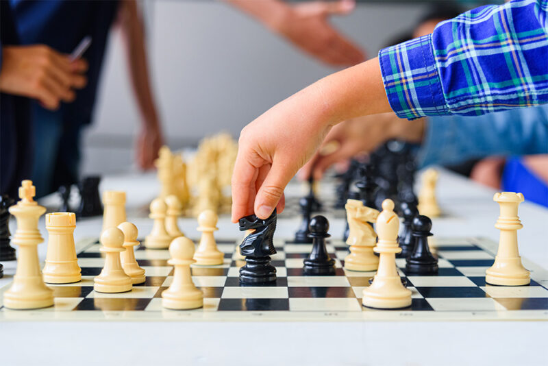 Child moving horse during chess tournament