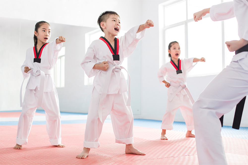 Young Chinese instructor teaching children Tae Kwon Do