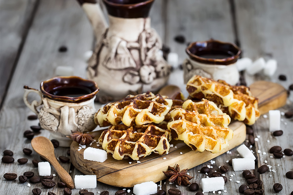 Homemade liege Belgian waffles with sugar pearls and coffee on an old wooden background