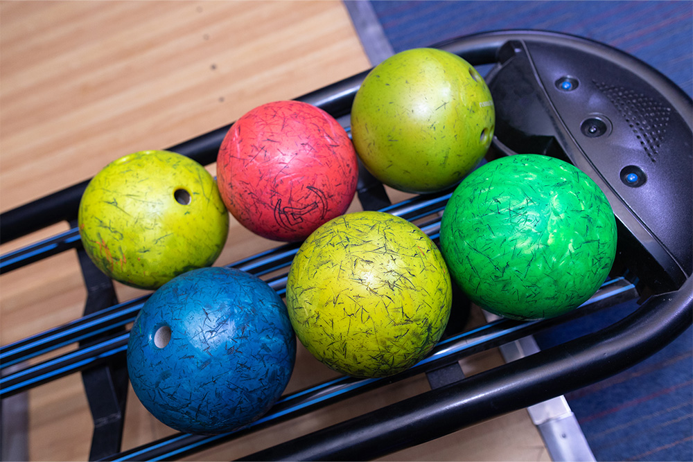 bowling balls lined neatly on a rack 