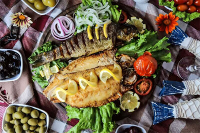 Fried and grilled fish with onion, tomato and lemon slices