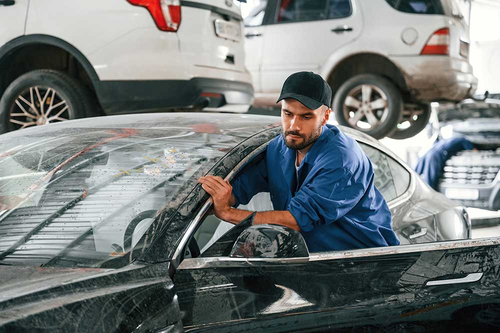 A mechanic moving a car for its maintenance