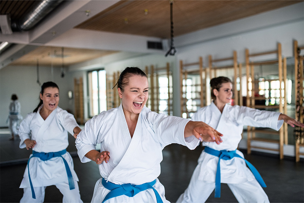 A group of young women practising karate indoors in the gym.