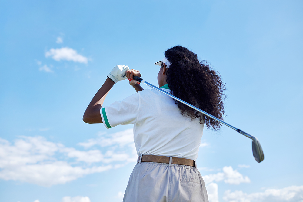 a woman playing golf at the best golf club in abu dhabi