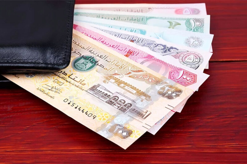 United Arab Emirates Dirham in the black wallet on a wooden background