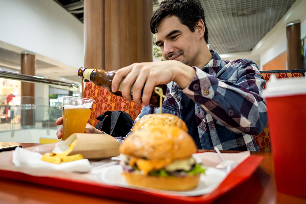 men eating burger and pouring drink at the best burger joint in Dubai