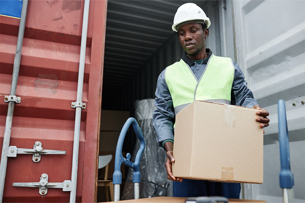 Worker unloading courier from a container at shipping docks