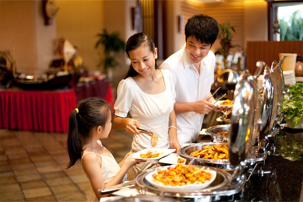 Mother helping her daughter to make her plate at buffet