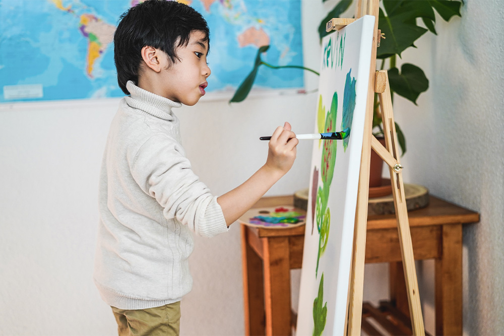 A young boy painting on a canvas