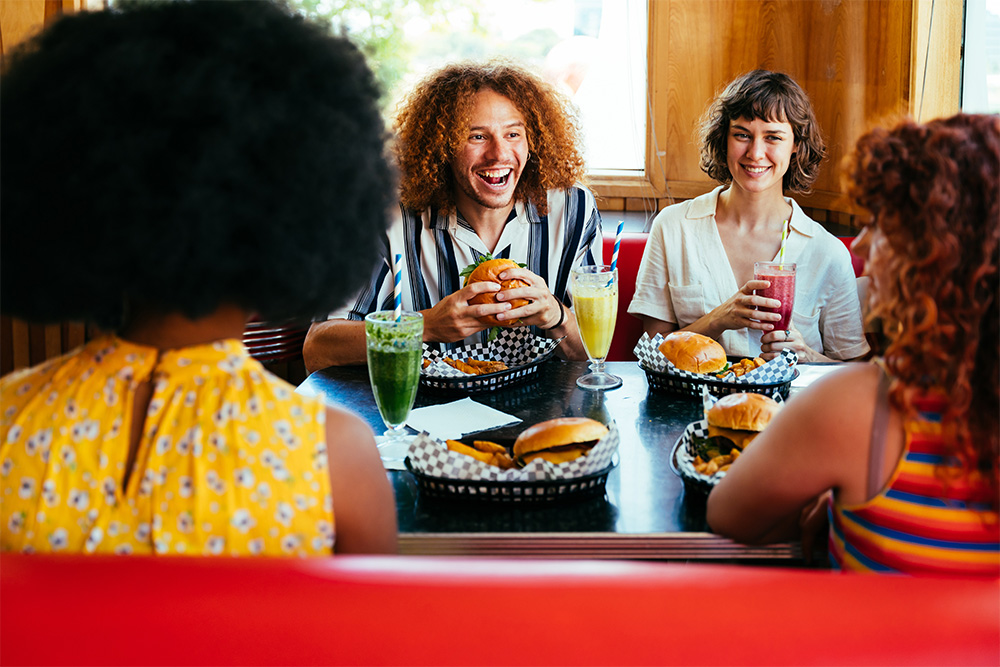 Friends eating burger with different drink and shake