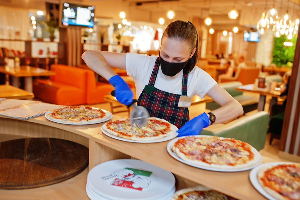 A server cutting pizza at an Italian restaurant