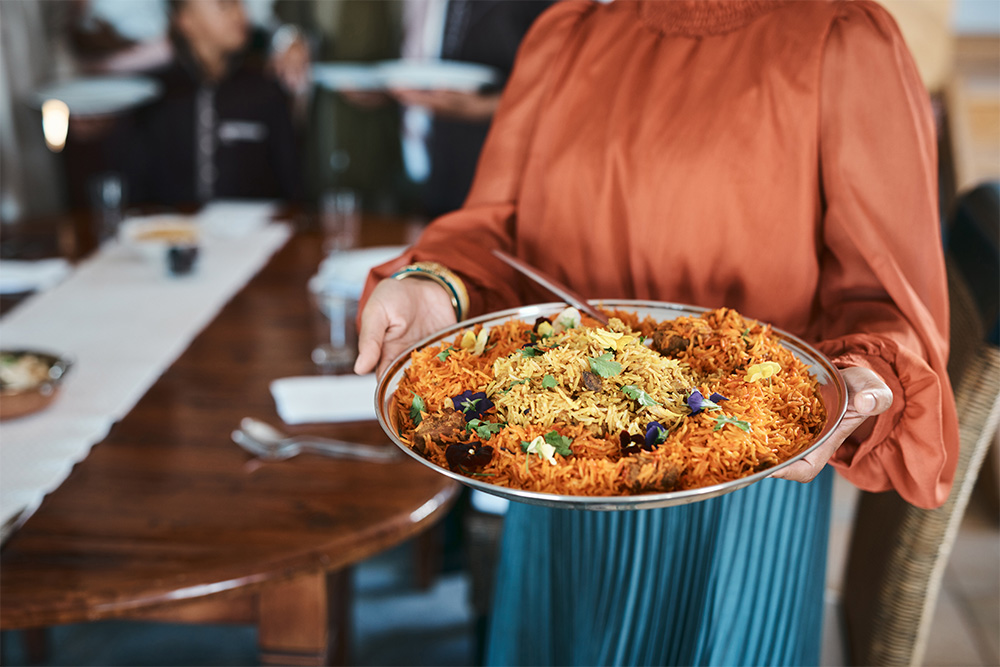 A woman serving Indian food in Asha’s