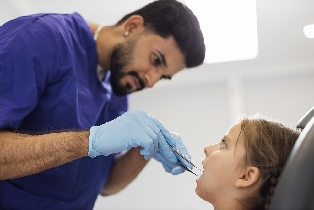 A male dentist examining a child’s teeth