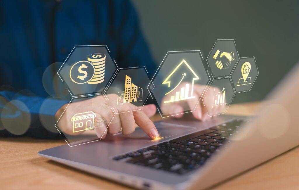 Hands typing on a laptop with digital icons representing financial growth, property management, and client relationship strategies, illustrating the concept of building and maintaining a real estate client database.