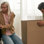 A couple unpacking boxes in their new home, carefully arranging personal items while settling in. This image could be used in a blog post for Property Finder’s Buyers and Renters guides, illustrating the moving process and making a new house feel like home.